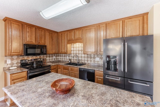 kitchen with a textured ceiling, a sink, decorative backsplash, black appliances, and brown cabinetry