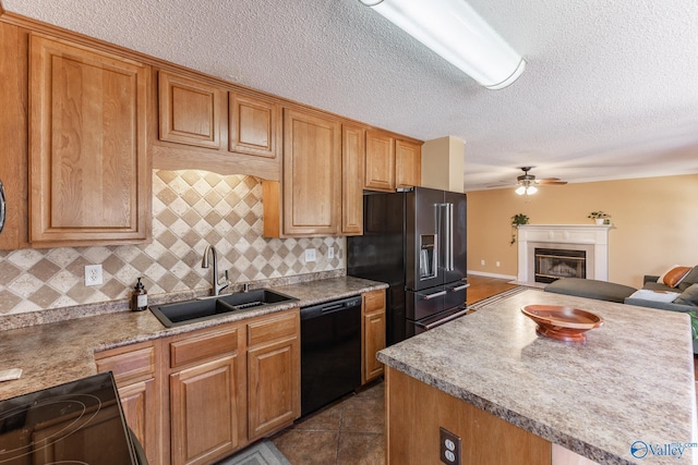 kitchen featuring a sink, a ceiling fan, open floor plan, black appliances, and a glass covered fireplace