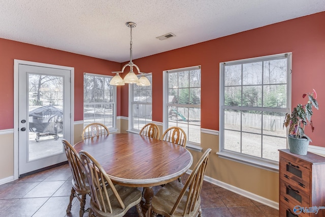 dining room featuring dark tile patterned flooring, visible vents, a textured ceiling, and baseboards