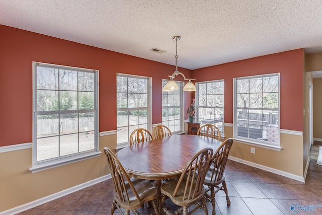 dining area featuring baseboards, a textured ceiling, visible vents, and a wealth of natural light