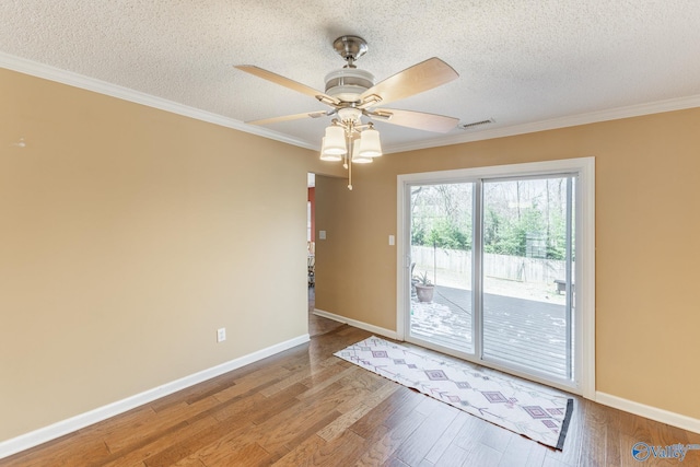 spare room with ornamental molding, a textured ceiling, baseboards, and wood finished floors