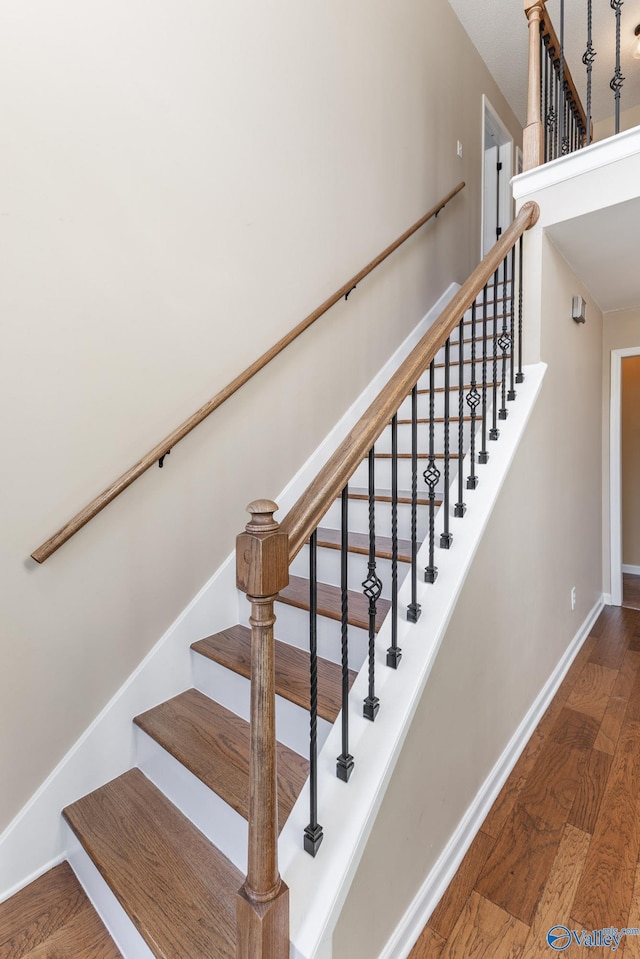 stairs featuring wood finished floors and baseboards