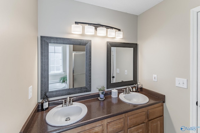 full bathroom with a sink, a shower stall, and double vanity