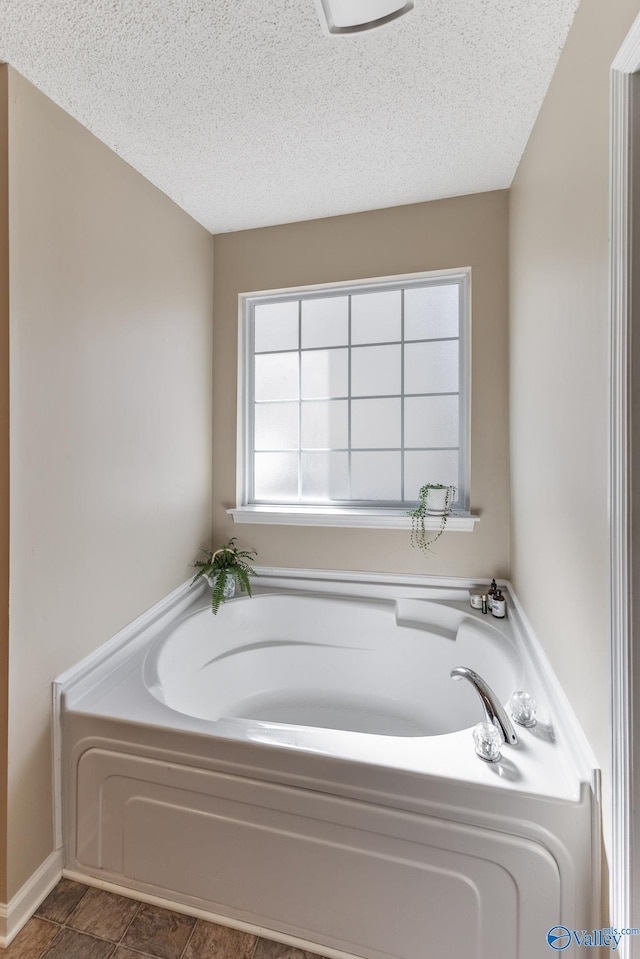 full bath featuring a garden tub and a textured ceiling