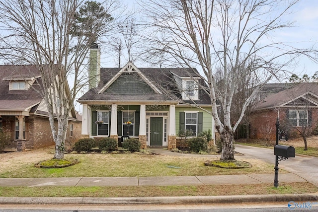 craftsman-style house with a front yard, driveway, and a chimney