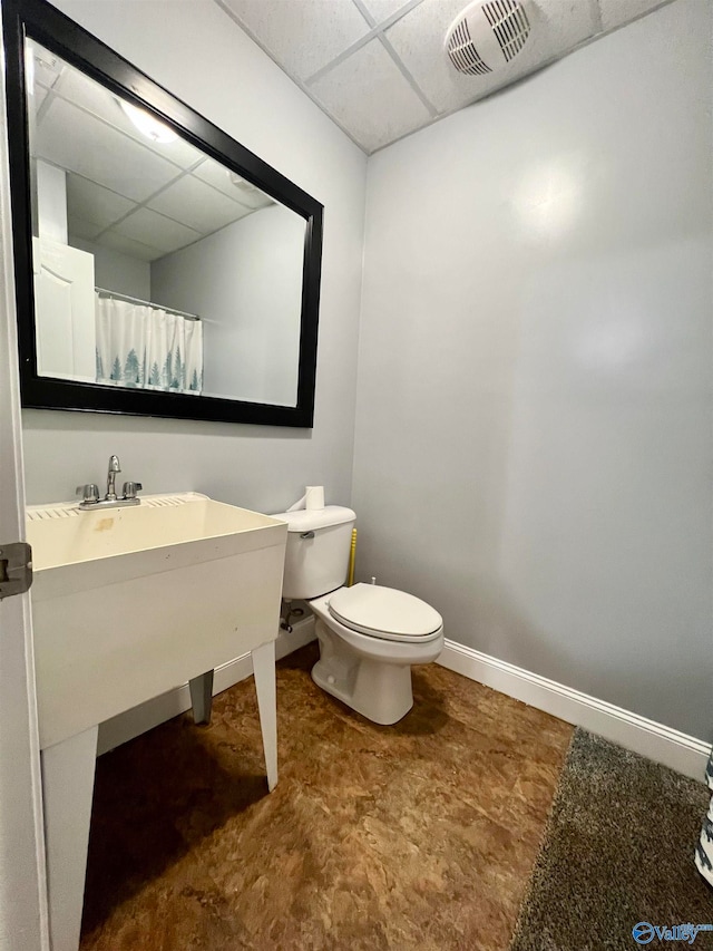 bathroom with toilet and a drop ceiling