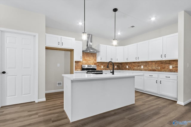 kitchen with wall chimney exhaust hood, a center island with sink, white cabinets, and electric stove