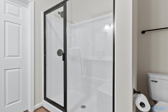 bathroom featuring toilet and a shower with door