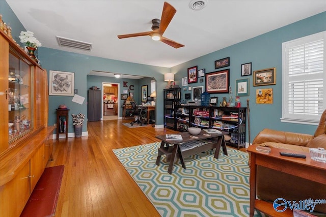 living area featuring visible vents, baseboards, a ceiling fan, and hardwood / wood-style flooring