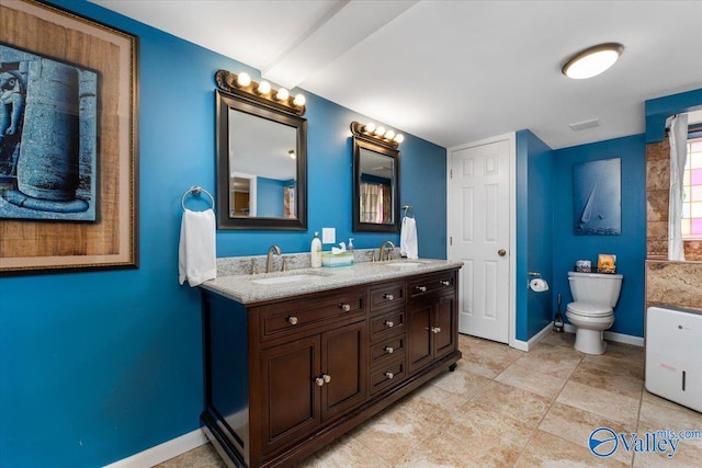 full bathroom with double vanity, toilet, baseboards, and a sink