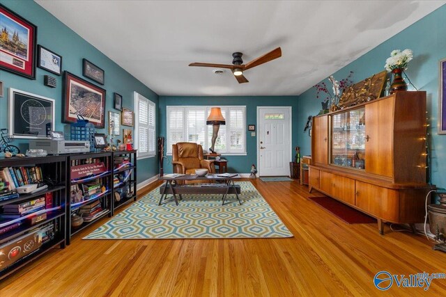 sitting room with a ceiling fan, wood finished floors, and baseboards