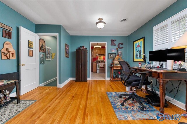 home office with visible vents, baseboards, and wood finished floors