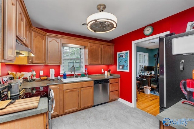 kitchen with baseboards, a sink, under cabinet range hood, appliances with stainless steel finishes, and brown cabinets