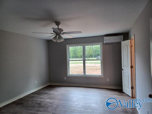 empty room with hardwood / wood-style floors, a wall mounted air conditioner, and ceiling fan