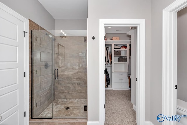 bathroom with a shower with door and toilet