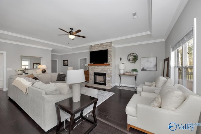 living room with ceiling fan, dark hardwood / wood-style floors, crown molding, a tray ceiling, and a fireplace