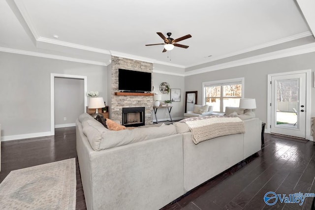 living room featuring ceiling fan, dark hardwood / wood-style flooring, crown molding, a tray ceiling, and a fireplace