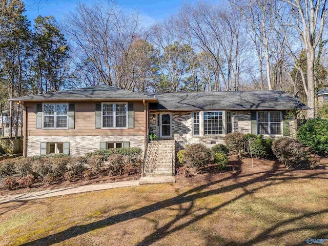 split level home featuring a front lawn and brick siding