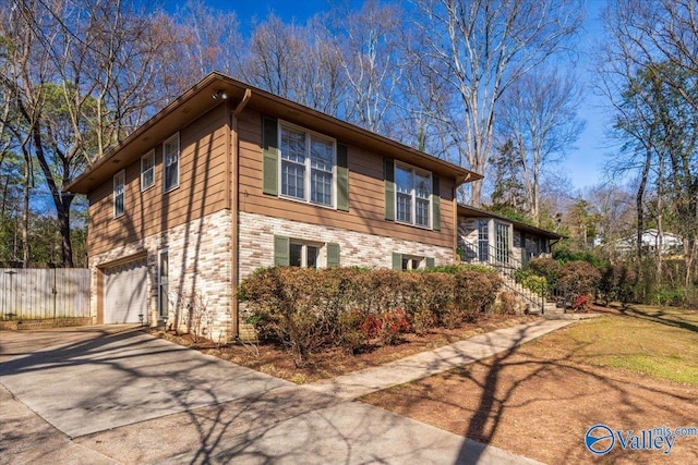 view of side of property with driveway, an attached garage, and fence