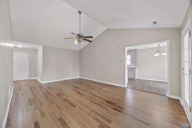 unfurnished living room with vaulted ceiling, ceiling fan with notable chandelier, light wood-style floors, and visible vents