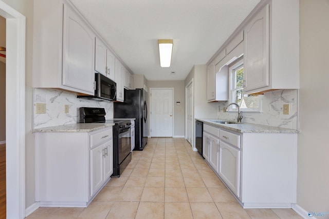 kitchen with a sink, light stone counters, black appliances, and white cabinets