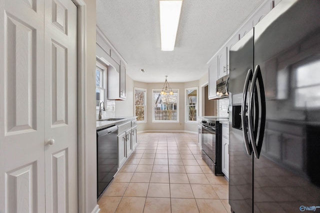 kitchen featuring light tile patterned flooring, a sink, black appliances, light countertops, and a chandelier