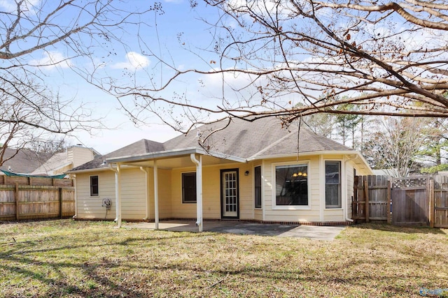 back of house featuring a fenced backyard, a lawn, a patio, and roof with shingles