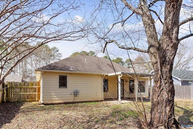 rear view of property featuring fence and a shingled roof