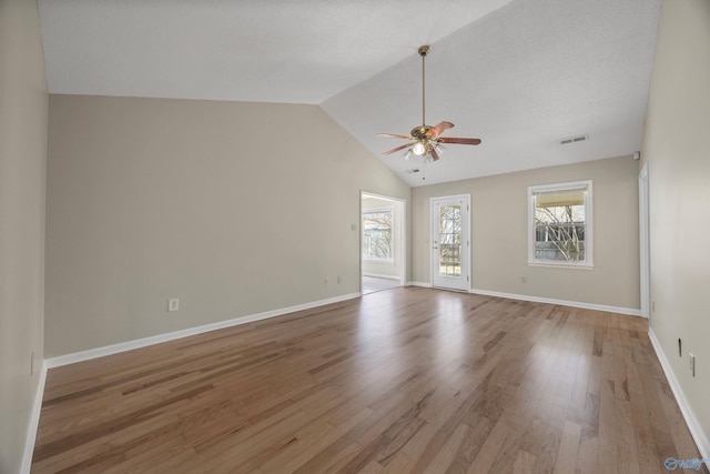 unfurnished room with baseboards, visible vents, lofted ceiling, light wood-style flooring, and ceiling fan