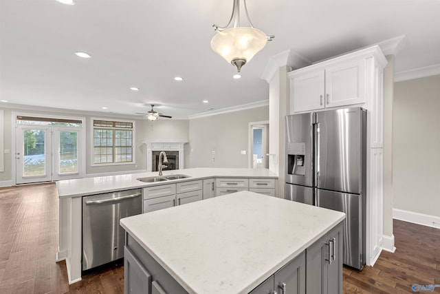 kitchen featuring appliances with stainless steel finishes, a center island, white cabinetry, sink, and kitchen peninsula