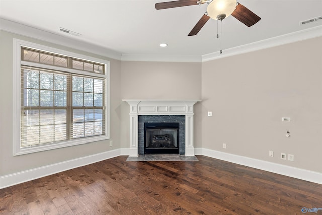 unfurnished living room with ceiling fan, dark wood-type flooring, a tile fireplace, and ornamental molding