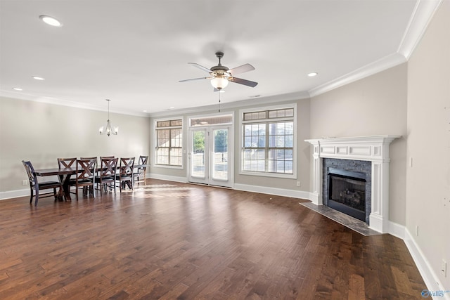 living room featuring ceiling fan with notable chandelier, dark wood-type flooring, crown molding, and a premium fireplace