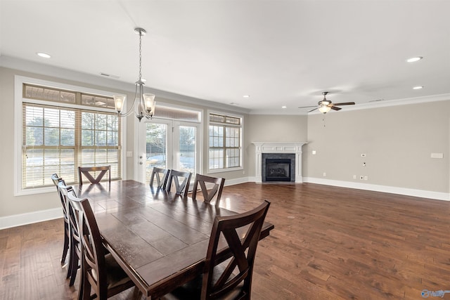 dining area with dark hardwood / wood-style flooring, crown molding, and ceiling fan with notable chandelier