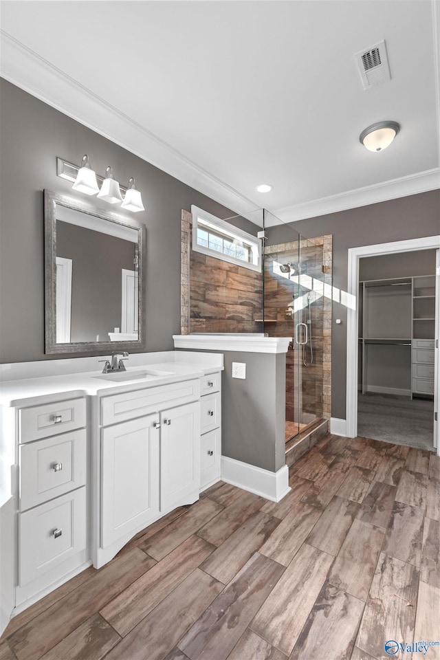 bathroom with a shower with shower door, vanity, and crown molding