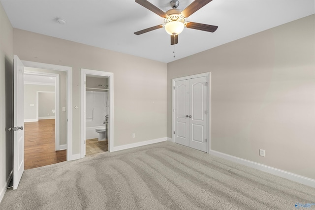 unfurnished bedroom with light carpet, ceiling fan, a closet, and ensuite bath