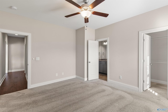 unfurnished bedroom featuring ceiling fan, ensuite bath, and light carpet