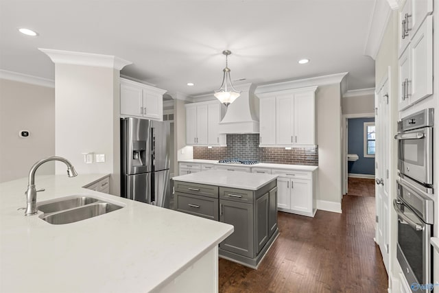 kitchen with custom exhaust hood, appliances with stainless steel finishes, sink, and white cabinetry