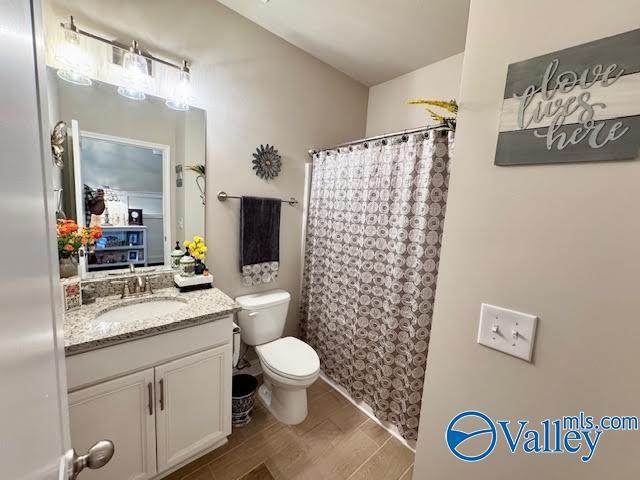 full bathroom with curtained shower, toilet, vanity, and wood tiled floor