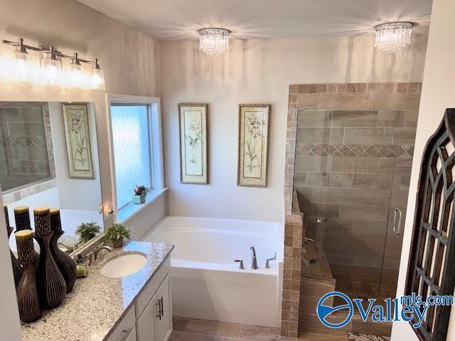 bathroom featuring vanity, a shower stall, a bath, and a chandelier