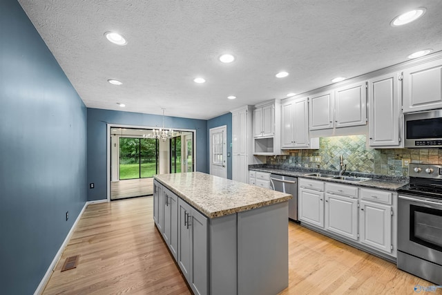 2211 Pumpkin Center Rd NE, Fort Payne, AL 35967 - kitchen with appliances with stainless steel finishes, a sink, a center island, a textured ceiling, and a chandelier