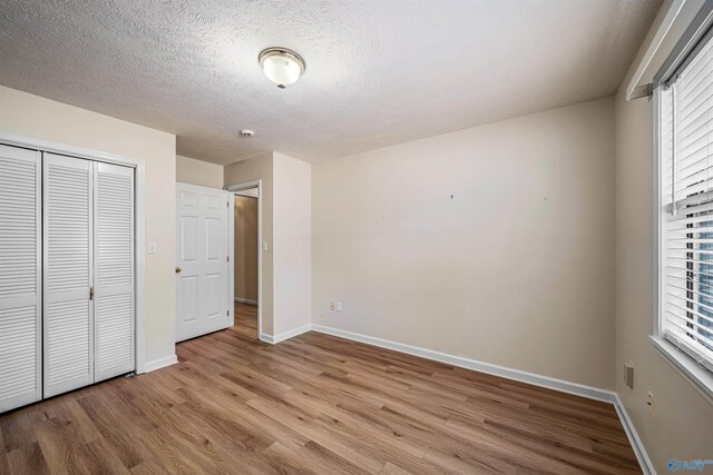 2211 Pumpkin Center Rd NE, Fort Payne, AL 35967 - unfurnished bedroom with light wood-style floors, baseboards, a textured ceiling, and a closet