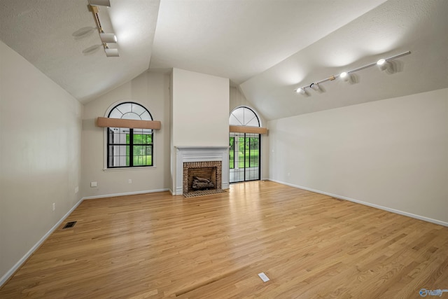 2211 Pumpkin Center Rd NE, Fort Payne, AL 35967 - unfurnished living room with track lighting, light wood finished floors, a fireplace, baseboards, and high vaulted ceiling