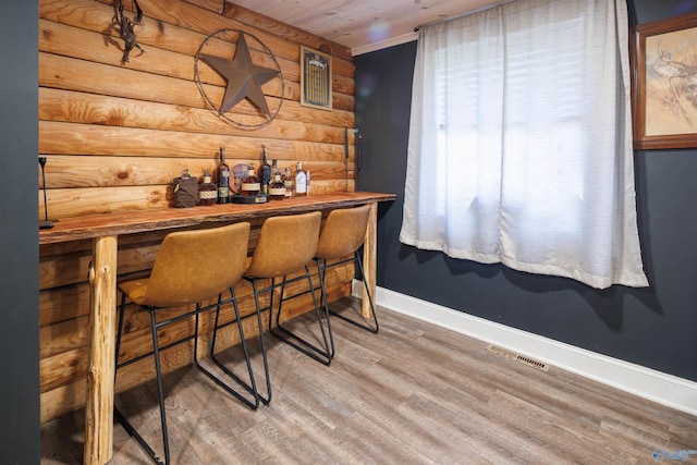 bar featuring wood ceiling, wooden counters, wood-type flooring, and rustic walls