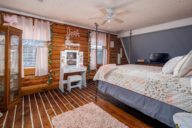 bedroom with log walls, ceiling fan, a textured ceiling, and dark hardwood / wood-style flooring