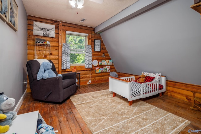 bedroom featuring lofted ceiling, rustic walls, dark hardwood / wood-style floors, and a crib