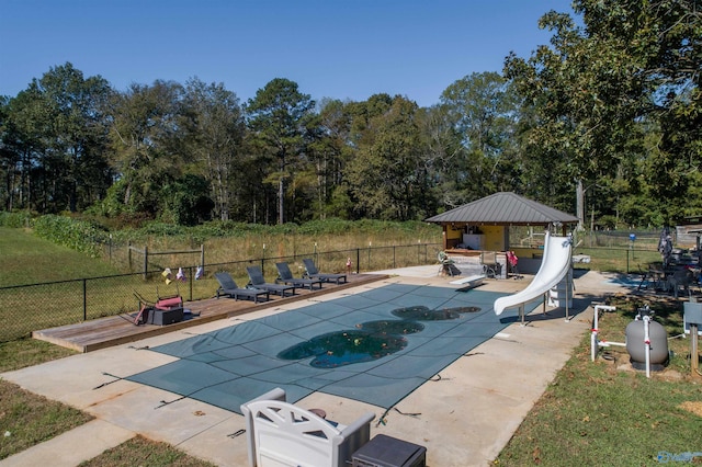 view of pool with a yard, a wooden deck, a gazebo, a water slide, and a patio area