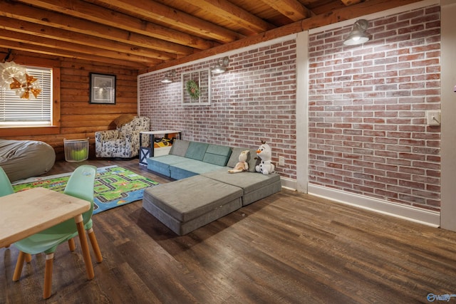 living room with dark hardwood / wood-style floors, beamed ceiling, and brick wall