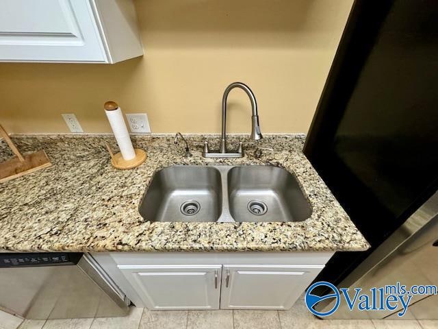 details featuring light stone countertops, white cabinetry, sink, and light tile patterned floors