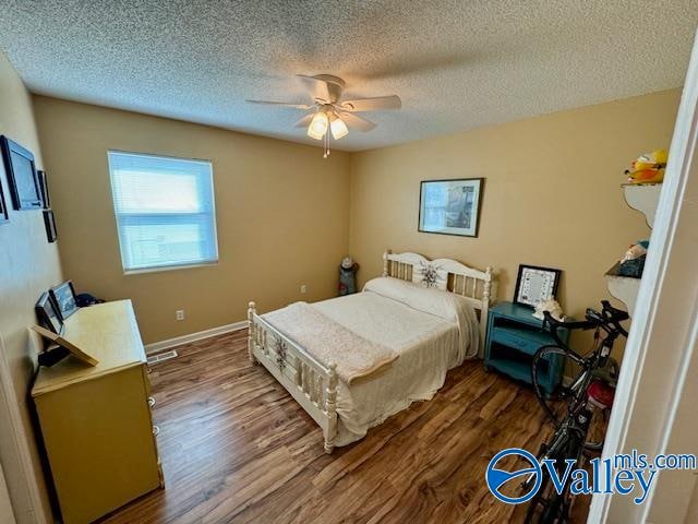 bedroom featuring ceiling fan, hardwood / wood-style floors, and a textured ceiling