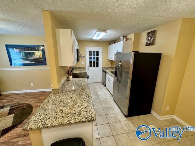 kitchen with black appliances, white cabinetry, and a textured ceiling